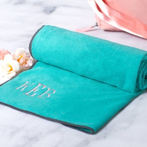 May include: A teal microfiber yoga towel with gray edging and the monogram "KTP" embroidered in pink.