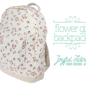 May include: A white canvas backpack with a floral print featuring pink flowers. The backpack has a zippered front pocket and adjustable straps. The text "flower girl backpacks" and "Joyful Tidings BRIDAL BOUTIQUE" is printed on the image.