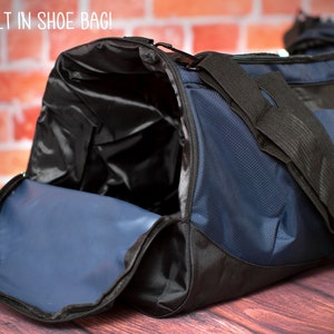 May include: A blue and black duffel bag with a built-in shoe bag. The bag is open and the shoe bag is visible. The bag is sitting on a wooden surface.