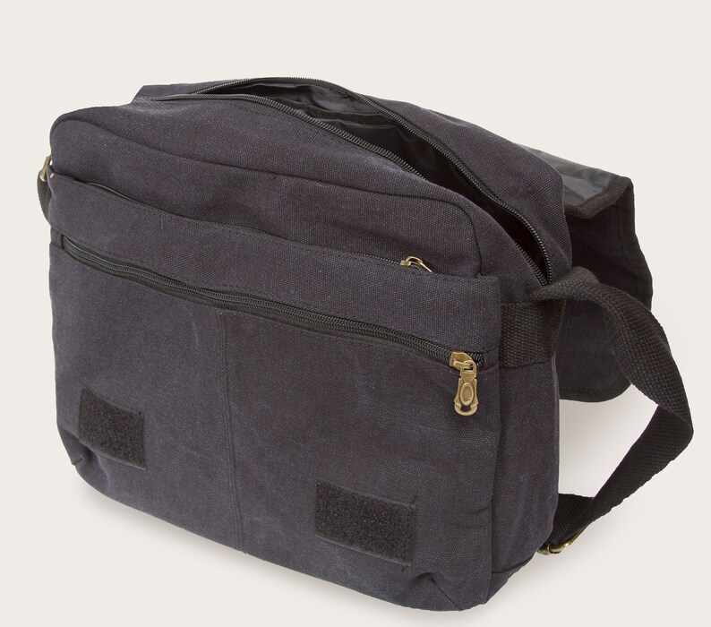 May include: A black canvas messenger bag with a zippered pocket and two velcro closures. The bag has a long adjustable strap.