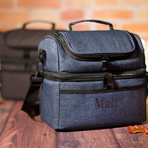 May include: A blue insulated lunch bag with a black zipper and handle. The bag has a personalized name, "Matt", embroidered on the front.