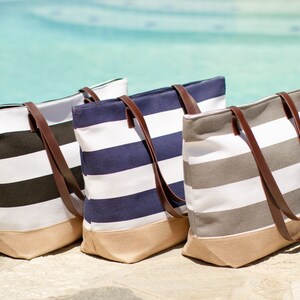 Puede incluir: Tres bolsas de lona a rayas con asas de cuero marr&oacute;n. Las bolsas son de color negro y blanco, azul marino y blanco, y gris y blanco.