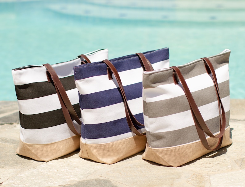 Puede incluir: Tres bolsas de lona a rayas con asas de cuero marr&oacute;n. Las bolsas son de color negro y blanco, azul marino y blanco, y gris y blanco.