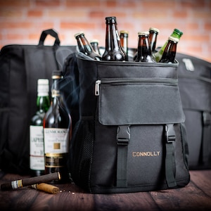 K&ouml;nnte beinhalten: Schwarzer isolierter Rucksack mit einer Rei&szlig;verschlusstasche vorne und dem eingestickten Wort "CONNOLLY" auf der Vorderseite. Der Rucksack ist mit Bierflaschen gef&uuml;llt.