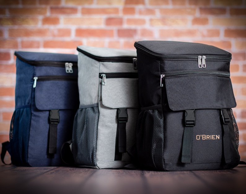 K&ouml;nnte beinhalten: Drei isolierte Rucks&auml;cke in verschiedenen Farben: marineblau, grau und schwarz. Der schwarze Rucksack hat den Text "O'BRIEN" auf der Vorderseite.