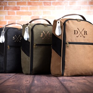 May include: Three personalised golf shoe bags in black, green and brown with embroidered initials and crossed golf clubs. Each bag has a zipped pocket and a shoe horn.