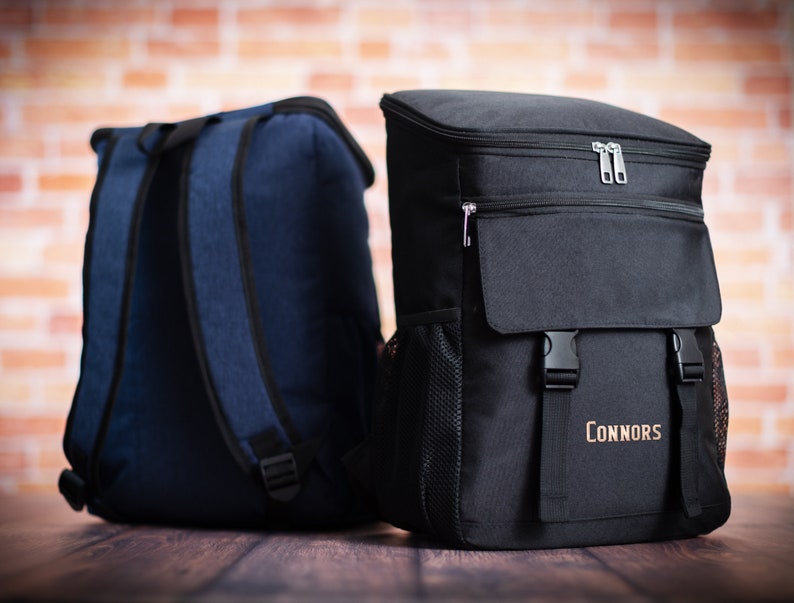 K&ouml;nnte beinhalten: Zwei Rucks&auml;cke, einer blau und einer schwarz. Der schwarze Rucksack hat eine Rei&szlig;verschlusstasche vorne und den Text "Connors" vorne aufgedruckt.