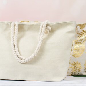 May include: Two canvas tote bags. One is plain white with rope handles. The other has a gold pineapple print.