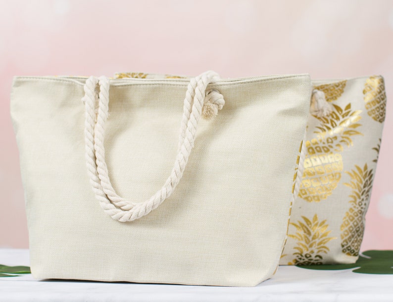 May include: Two canvas tote bags. One is plain white with rope handles. The other has a gold pineapple print.
