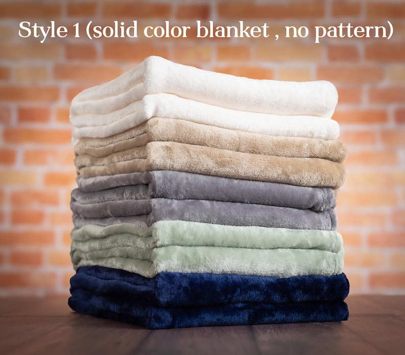 May include: A stack of eight solid color fleece blankets in various colors, including white, beige, gray, green, and navy blue.  Style 1 (solid color blanket, no pattern).