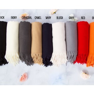 May include: Ten different colored scarves with fringe. The colors are black, ivory, charcoal, camel, navy, blush, gray, red, orange, and white.