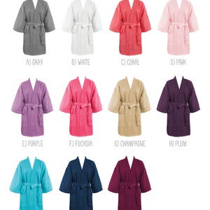 May include: A collection of eleven robes in various colors including gray, white, coral, pink, purple, fuchsia, champagne, plum, tropical blue, navy, and berry. Each robe features a tie belt, two front pockets, and three-quarter length sleeves.