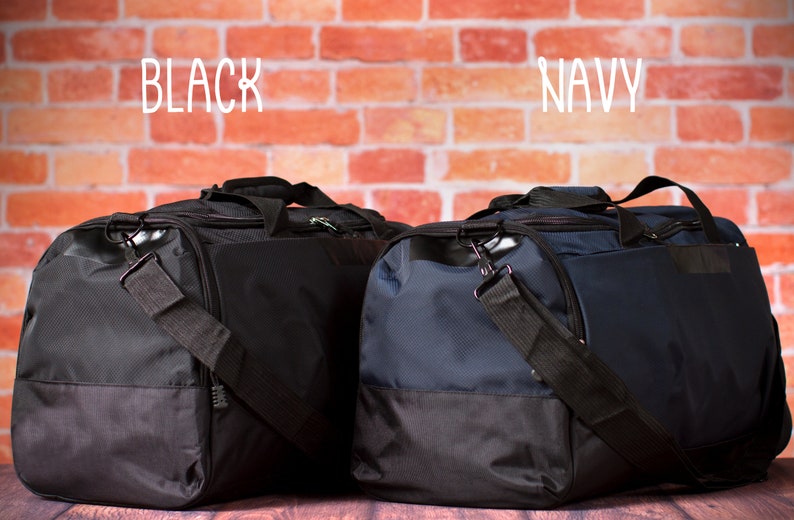 K&ouml;nnte beinhalten: Zwei Reisetaschen, eine schwarz und eine marineblau, mit schwarzen Akzenten. Die Taschen stehen auf einer Holzoberfl&auml;che vor einer Backsteinwand. Die W&ouml;rter "BLACK" und "NAVY" stehen &uuml;ber den Taschen.