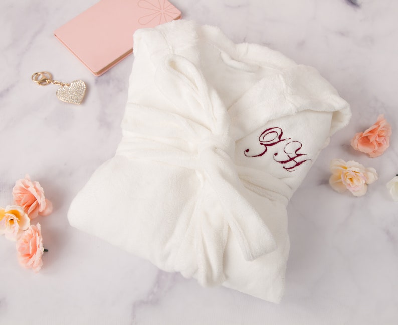 May include: White plush robe with a burgundy embroidered monogram "S.H." on the front.