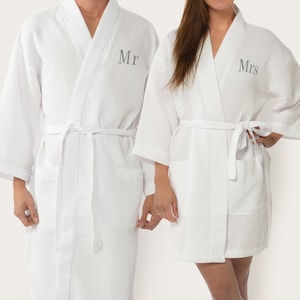 May include: Two white waffle weave robes with embroidered text, one says "Mr." and the other says "Mrs."