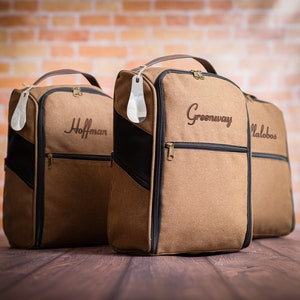 May include: Three brown canvas travel bags with black accents and zippered compartments. The bags have personalised names embroidered on the front: Hoffman, Greenway, and Malobos.