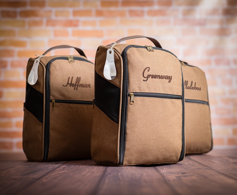 May include: Three brown canvas travel bags with black accents and zippered compartments. The bags have personalised names embroidered on the front: Hoffman, Greenway, and Malobos.