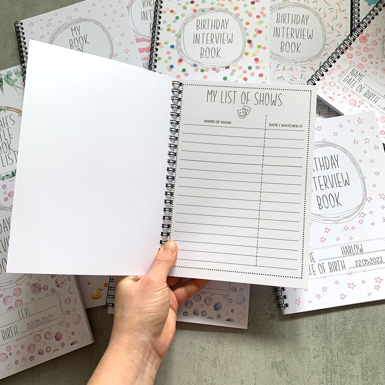 Puede incluir: Un libro de entrevistas de cumplea&ntilde;os con encuadernaci&oacute;n en espiral y dise&ntilde;o de confeti colorido. La p&aacute;gina abierta muestra una lista titulada "MY LIST OF SHOWS" con espacios para el nombre del programa y la fecha. Se ven otros libros con dise&ntilde;os similares.