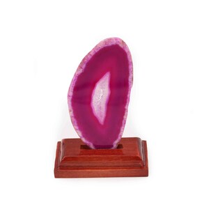 May include: A pink agate slice on a wooden stand. The agate has a natural, white, crystal-like formation in the center.