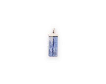 Puede incluir: Un colgante de plata con una piedra rectangular azul y blanca.
