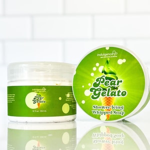 Pu&ograve; includere: Due barattoli di sapone montato profumato alla pera. I barattoli sono etichettati "Pear Gelato" e "Shower Icing Whipped Soap". I barattoli sono su uno sfondo di piastrelle bianche.