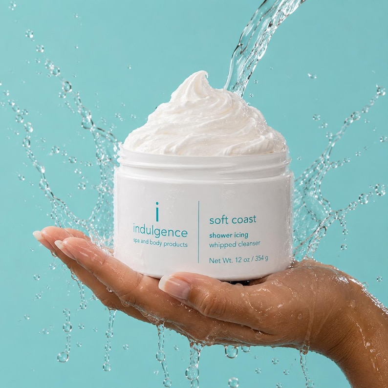 May include: A white plastic jar of Indulgence soft coast shower icing whipped cleanser with a peak of white cream on top. The label reads Indulgence spa and body products, soft coast, shower icing whipped cleanser, Net Wt. 12 oz / 354 g.