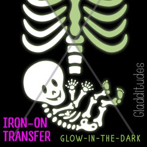 May include: Glow-in-the-dark iron-on transfer featuring a skeleton design with a baby skeleton inside. The design includes a rib cage, a heart, and the text "IRON-ON TRANSFER" and "GLOW-IN-THE-DARK" in pink and green.