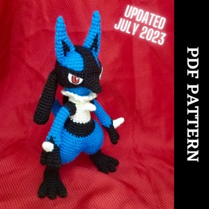 May include: Crocheted blue and black Pokemon Lucario amigurumi plush toy. The toy is standing on a red background. The text "UPDATED JULY 2023" is in the top right corner of the image. The text "PDF PATTERN" is in the top right corner of the image.