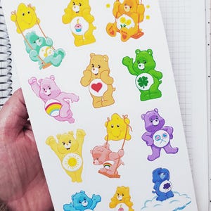 May include: A sheet of colorful Care Bear stickers. The stickers feature various Care Bears in different poses, with hearts, rainbows, and other designs. The text "Beyond Paper" is visible in the upper left corner.