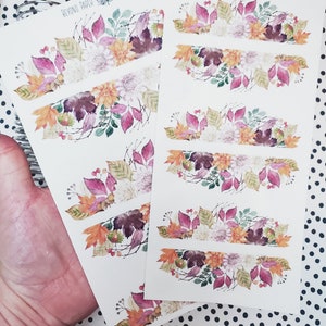 May include: A sheet of stickers with watercolor illustrations of fall foliage, flowers, and berries. The stickers are arranged in rows and feature a variety of colors, including pink, purple, orange, and green. The text "Beyond Paper Flowers" is printed at the top of the sheet.