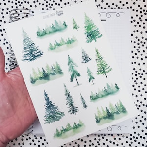 May include: A sheet of watercolor stickers featuring various green trees and forest scenes. The stickers are labeled "Beyond Paper Flowers".