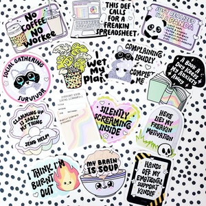 May include: A collection of colorful stickers with various humorous and relatable phrases. The stickers feature illustrations of raccoons, pandas, a plant, a book, a clam, a brain, a fire, and a laptop. The text on the stickers includes phrases like "No Coffee No Workee", "I Wet My Plan", "Just Realized I'm a Panda", "Clamming Up Is Sadly My Thing", "Silently Screaming Inside", "Here Lies My Freakin Motivation", "My Brain Is Soup", "I Think I'm Burnt Out", "This Def Calls For a Freakin Spreadsheet", "Complaining Loudly Complet Me", "A Book a Day Keeps My Anxiety Away", "Hands Off My Emotional Support Kindle", and "Social Gathering Survivor".