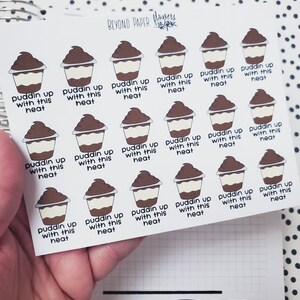 May include: A sheet of stickers featuring a cartoon illustration of a chocolate pudding cup with the text "puddin up with this heat" repeated on each sticker.