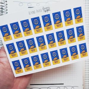 May include: A sheet of stickers featuring the Kraft Mac & Cheese box design. The stickers are blue, yellow, and orange. The text "mac & cheese" and "original flavor" are visible on each sticker. The sheet is labeled "BEYOND PAPER flowers".
