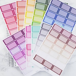 May include: A set of colorful blank label stickers with a variety of colors including pink, purple, blue, green, yellow, and orange. The stickers are arranged in a fan shape and have a white background with a black border. The stickers are labeled "bound paper twins" and "designed by bound paper twins".