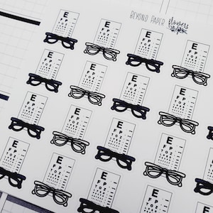 May include: A sheet of stickers featuring eye charts with glasses. The stickers are white with black text and black outlines. The text on the eye charts reads "E, FP, TOZ". The stickers are arranged in a grid pattern.
