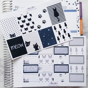 May include: A set of black and white cat-themed planner stickers with the text "meow" and "Beyond Paper Flowers". The stickers feature various cat designs, including paw prints, stars, and stripes.
