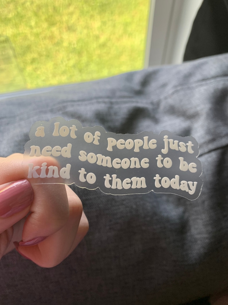 Op de afbeelding: Een witte sticker met de tekst "a lot of people just need someone to be kind to them today" in een retro-lettertype.