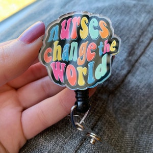 May include: A colorful badge reel with the text "Nurses Change the World" in a retro font. The badge reel is black and has a silver clip.