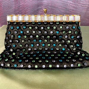 May include: A vintage black beaded evening bag with a gold frame and clasp. The bag is covered in a delicate black mesh, adorned with colorful iridescent beads in shades of blue, green, and silver. The frame is gold with a pearlescent top.