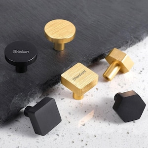 May include: A collection of cabinet knobs in various shapes and finishes, including round, square, and hexagonal designs. The hardware features brushed gold and matte black metal surfaces, with the text SSHardware printed on several pieces.