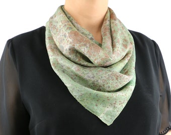 May include: A green silk scarf with a brown and white marbled pattern. The scarf is folded and draped around a person's neck.