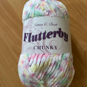 Pode incluir: Uma caneca de cerâmica branca com uma alça preta e o texto "But First, Coffee" em negrito preto. A caneca está sobre um fundo desfocado, sugerindo um ambiente acolhedor.