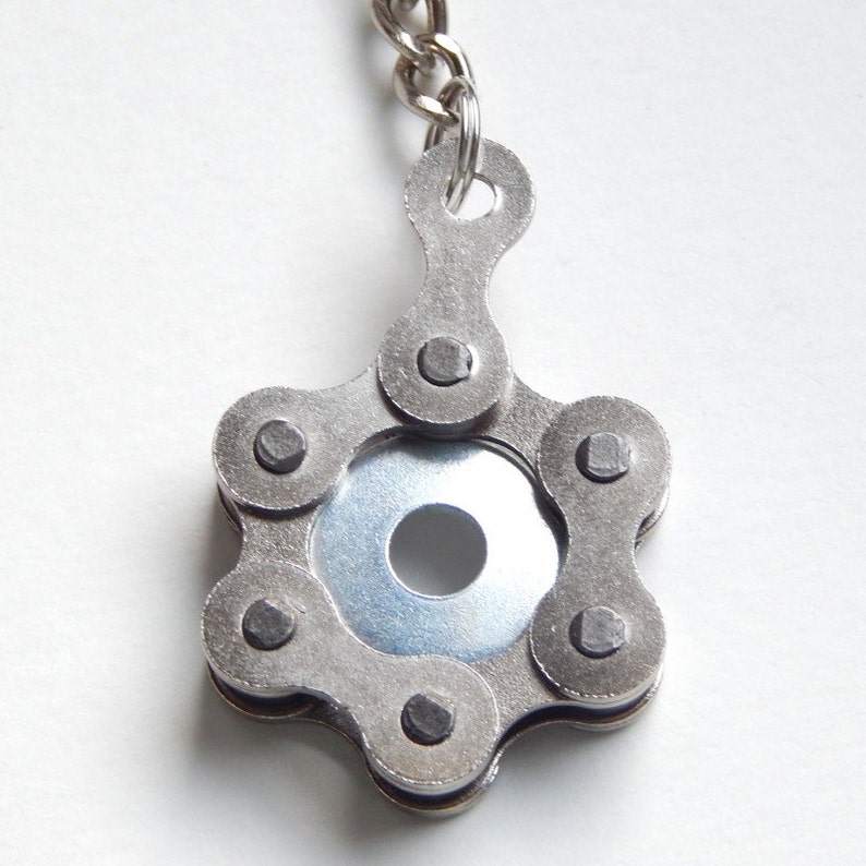 May include: A silver keychain made from a bicycle chain, shaped like a star with a round metal disc in the center.