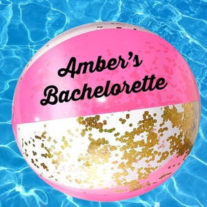 Peut inclure: Ballon de plage rose et blanc avec des paillettes dorées. Le ballon porte l'inscription "Amber's Bachelorette".