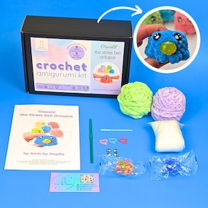 May include: A crochet amigurumi kit for an octopus stress ball. The kit includes a black box, yarn, a crochet hook, and a pattern. The image shows a finished blue octopus stress ball with a yellow bubble, and other colorful examples.