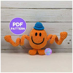 Peut inclure: Un jouet en peluche crocheté orange avec un corps rond, un chapeau bleu et de longs bras en spirale. Le jouet présente un sourire brodé noir et deux yeux noirs. Un graphique circulaire violet avec le texte blanc PDF PATTERN est visible.