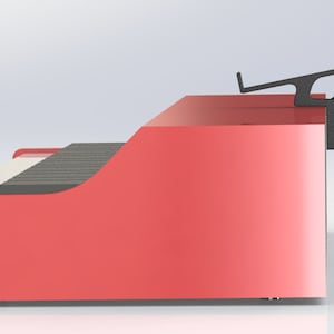 Puede incluir: Vista lateral de un soporte de teclado rojo con un soporte de tableta negro fijado en la parte superior. El soporte tiene un borde frontal curvo y una superficie superior plana.