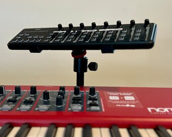 Puede incluir: Un controlador MIDI Korg nanoKONTROL2 negro montado sobre un teclado Nord rojo. El teclado tiene teclas blancas y controles negros. La imagen es un primer plano de los instrumentos musicales.