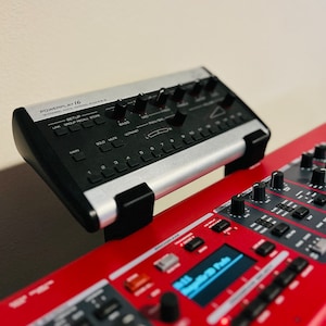 Puede incluir: Un mezclador personal digital de 16 canales plateado y negro con botones y perillas. El mezclador est&aacute; montado en un teclado rojo con una pantalla digital que dice "All Registers File".